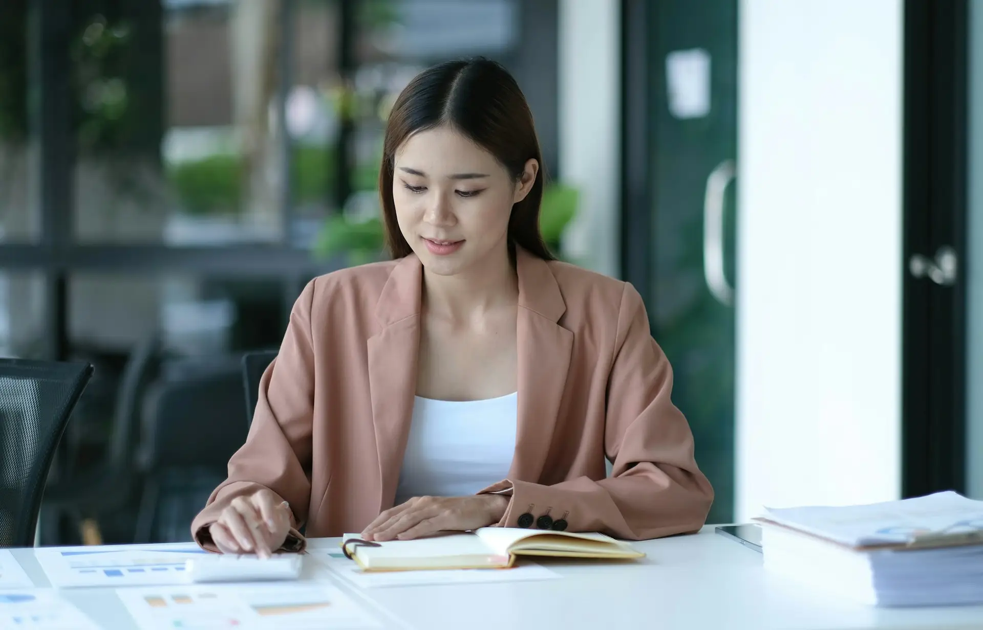 Business women using calculator at working with financial report.